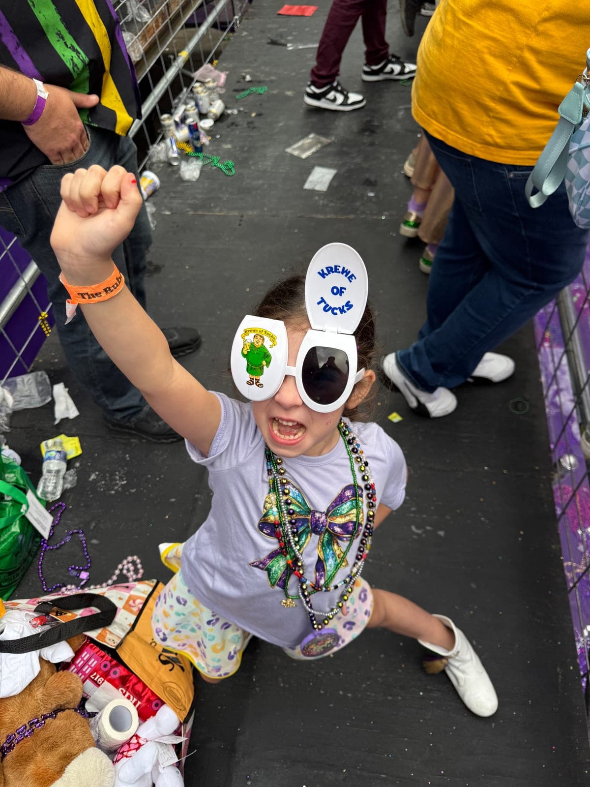 Silvana's daughter beaming in oversized Krewe of Tucks novelty sunglasses, covered in beads.