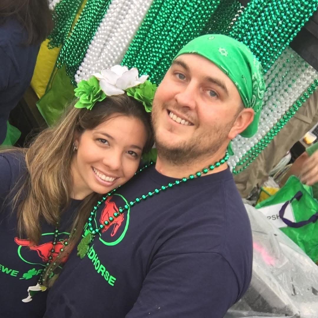 Silvana and Shaun cheek to cheek at a St. Patrick's Day parade, her in a green flower crown, him in a green bandana.